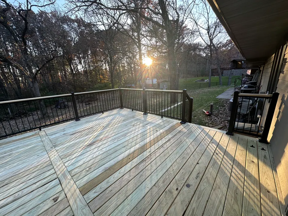 Pressure-treated deck with black metal railing at sunset
