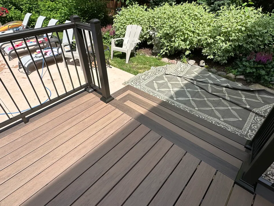 Composite deck with black railing beside a garden