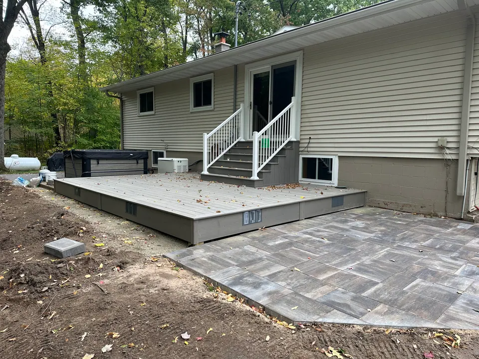 Ground-level deck with paver patio and white stair railing