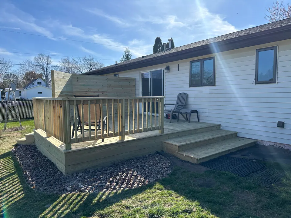 Pressure-treated deck with railing and stairs, rear view of home