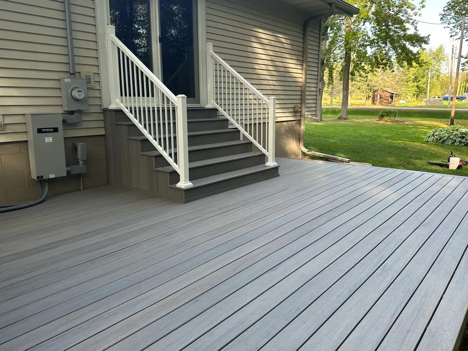 Composite deck with white railing and stairs to a side door